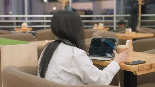 Close Up of Woman Using Tablet While Drinking Juice in Cafe with People Around