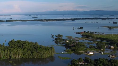 Aerial view of rural village area submerged in flood water. Landscape with hills in the background.