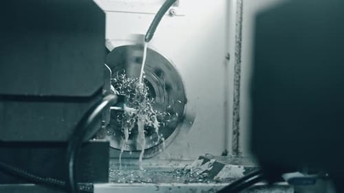 Close-up of metal lathe machine cutting metal with coolant spray