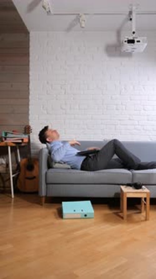 Vertical Video Man Feeling Exhausted and Taking a Break From Work Stretching His Arms While Lying on