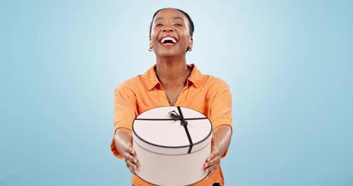 Femme noire, heureuse ou boîte cadeau comme cadeau, excitée ou souriante sur fond de studio bleu pour une fête