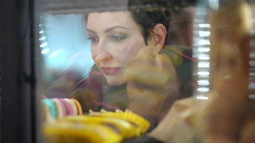 Woman Looks at Colorful Desserts in Bakery Display