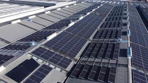 Drone flight over solar panel installation on factory rooftop