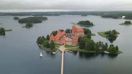 Aerial shot of the Trakai castle surrounded by trees over the Galves lake in Trakai, Lithuania