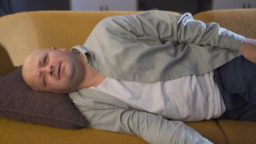 Un homme allongé sur le canapé en train de pleurer.