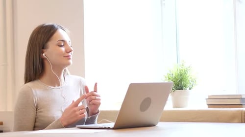 Woman Listening to Music at Table with Laptop