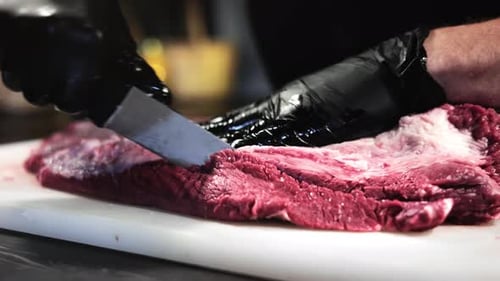 Butcher Slicing Brisket on Cutting Board