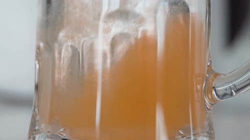Orange Liquid Being Poured into a Clear Mug