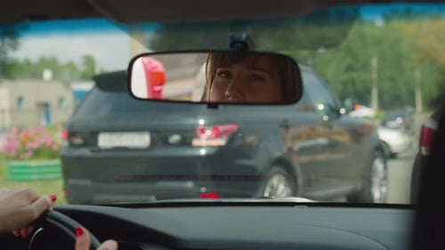 Reflection of Woman in Rear View Mirror on Windshield in Car