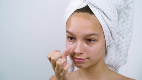 Adolescente appliquant une crème pour le visage après le bain