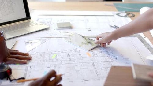 Architects Planning on Top of Blueprints in Office