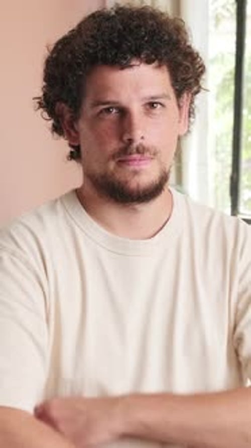Man Smiles Indoors with Arms Folded