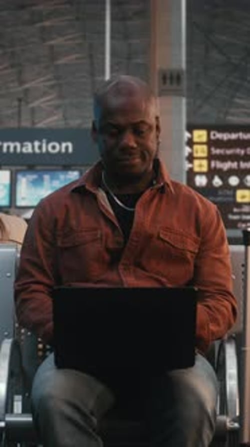 Focused Freelancer Working on Laptop at Airport Gate During Flight Delay