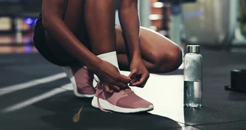 Hands, shoes and laces in gym for fitness, run or start exercise routine with water for health