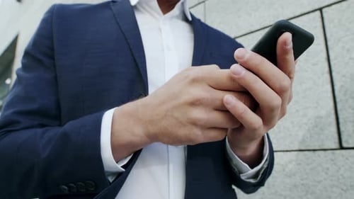 Close Up View Businessman In Suit Texting Message On Smartphone At City Street. Male Executive Us...