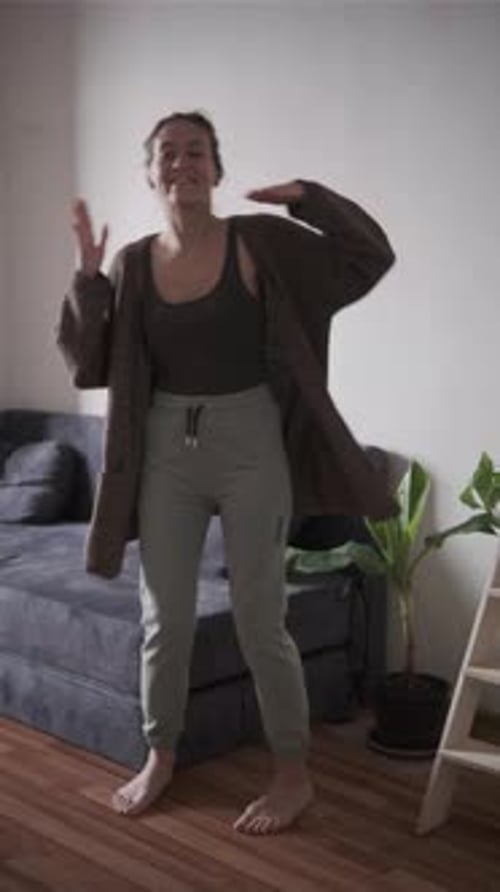 Cheerful Woman Dances in Living Room with Natural Light