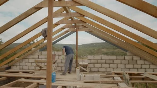 Man Working on Wood Framing of a Building