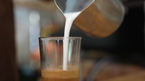 Milk Being Poured into Coffee in Glass
