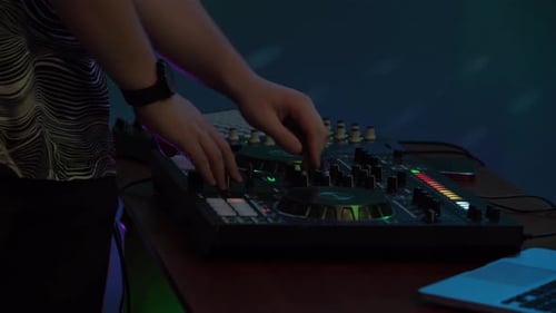 Close Up Shot Capturing Hands of a Man Playing and Mixing Music on a DJ Console Neon Colorful Lights