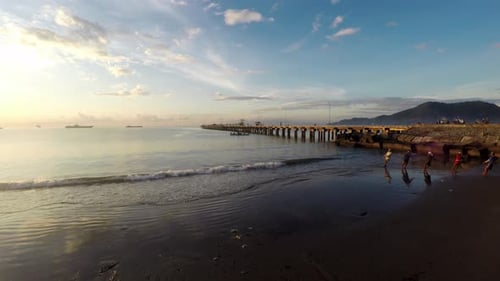 Drone aerial shot of a port, pier and ships on the horizon in the rays of the setting sun