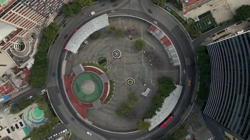Drone approaching roundabout in city of Mexico top down with cars and buildings