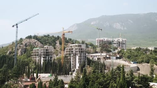 Construction cranes with new buildings under construction on the background of the mountain. Constru