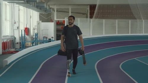Man with Prosthetic Leg Walks on Indoor Track