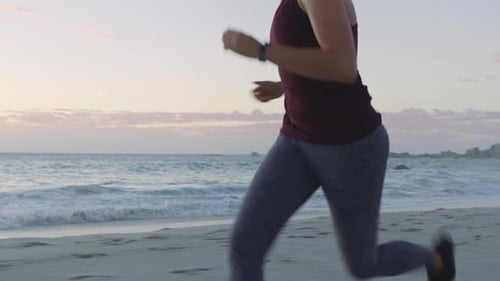 Runner, wellness or woman running at sunset on beach, ocean or sea for training, health or exercise
