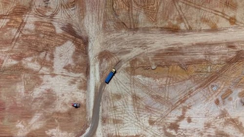 Aerial view of construction site with trucks and tire tracks