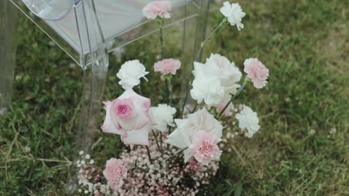 Closeup Floral Composition Near Transparent Plastic Chair Chair on Green Lawn Outdoor Wedding