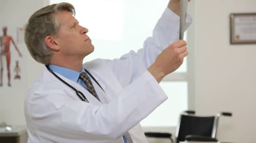 Doctor Examining X-ray and Making Notes in Office