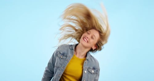 Happy, woman and whip hair in studio isolated on a blue background for natural beauty