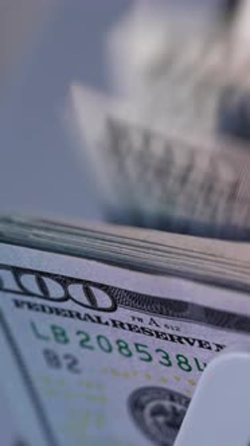 American currency hundred dollar bills falling on the holder of device. Close up.