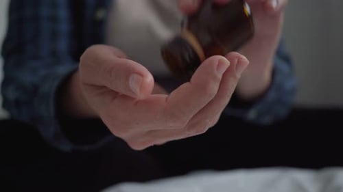 Un anciano se vierte tabletas de antibióticos en la mano