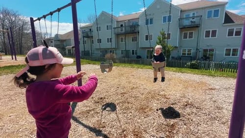 Kinder reiten auf einer Schaukel auf dem Spielplatz im Park