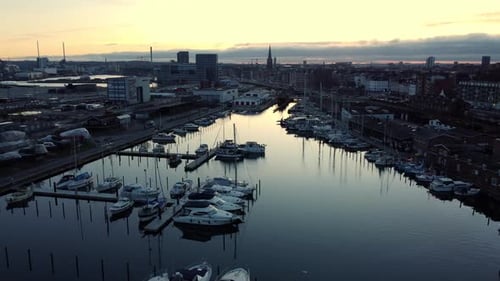 Aerial Dusk View Of Marina, Boats, Yachts, And Cityscape