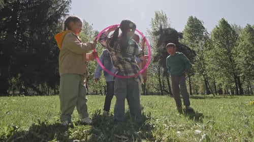 Children Play Hula Hoop Together in Spring Park