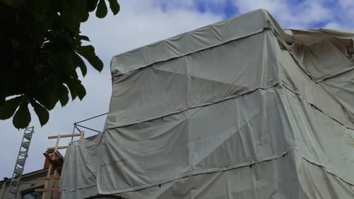 Sitio de construcción con andamios y lonas que cubren un edificio en desarrollo y