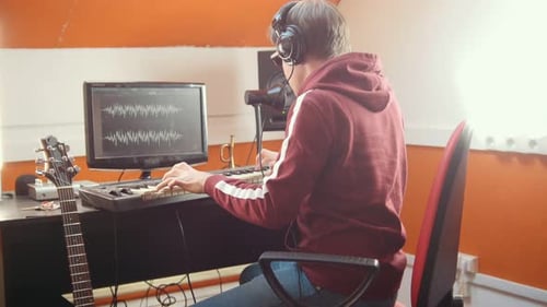 Young Man Plays Keyboard in a Home Studio