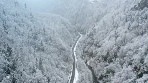 Aerial View of Snowy Mountain Valley with Winding Road and River