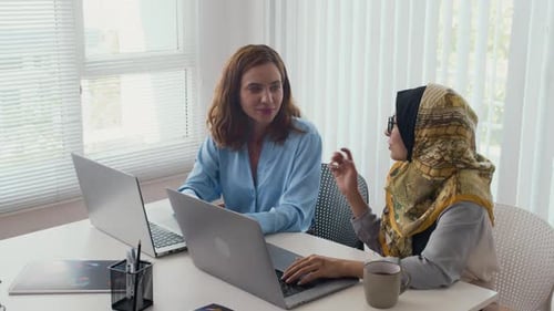 Colleagues Working On Computers In Office