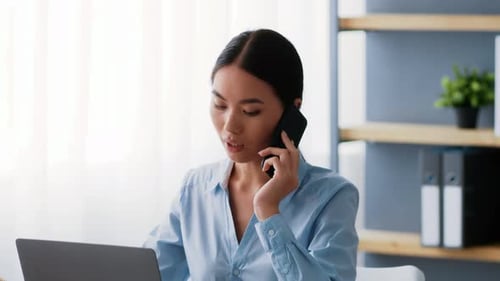 Business Woman Talking on Phone While Using Laptop
