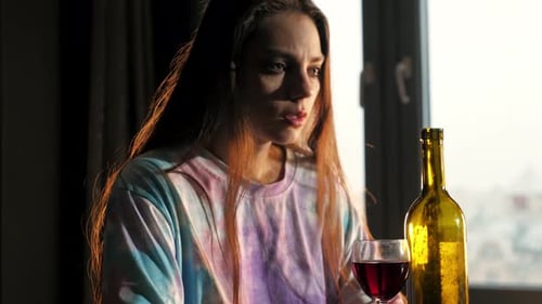 Uma lágrima escorre pela bochecha de uma garota que bebe e chora