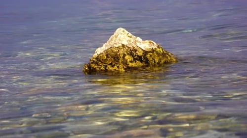 Golden rock washed by lake water on a sunny beautiful day in twilight
