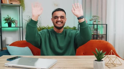 Man Waving and Smiling at Table Indoors