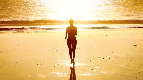 Slow motion shot of an Asian woman jogging on the beach
