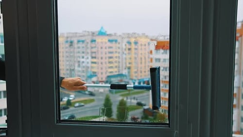 Fensterreiniger, der mit nassen Glasfenstern arbeitet. Nahaufnahme des Reinigungsfensters.