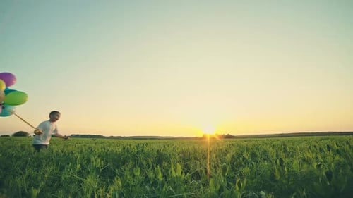 Happy Boy with Balloons Running on the Spring Field