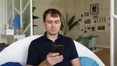 Man Sitting Indoors Using His Mobile Phone