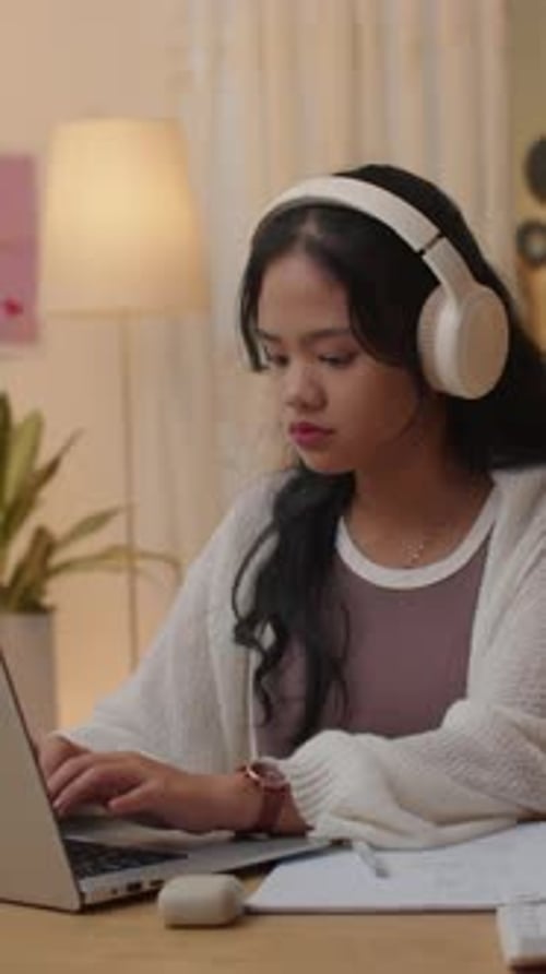 Focused Woman Typing at Laptop with Headphones